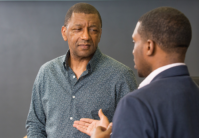 Dr. Stevenson stands in front of a chalkboard conversing with a student.