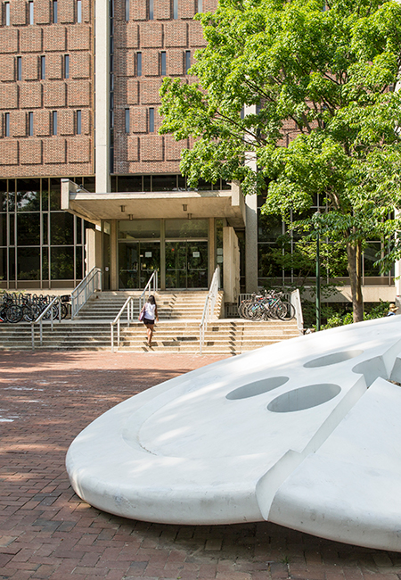 The iconic white button sculpture appears before Van Pelt Library and a green tree on Penn’s campus