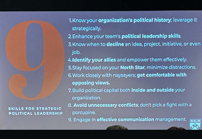 A presentation slide titled "9 Skills for Strategic Political Leadership" appears on a projector screen listing nine skills recommended for education leaders.