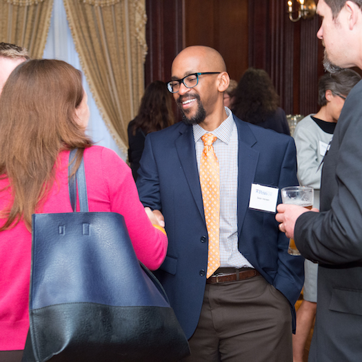 Male and female GSE alumni shaking hands at a networking event.
