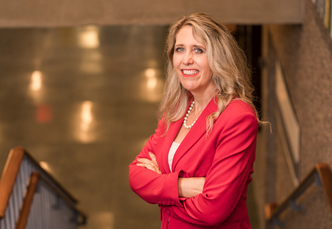 Amy Stornaiuolo poses in a red blazer in a stairwell.