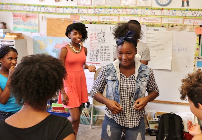 Children stand in a circle in a classroom. 