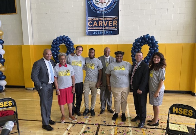 School leaders at Carver High School pose in front of Blue Ribbon banner