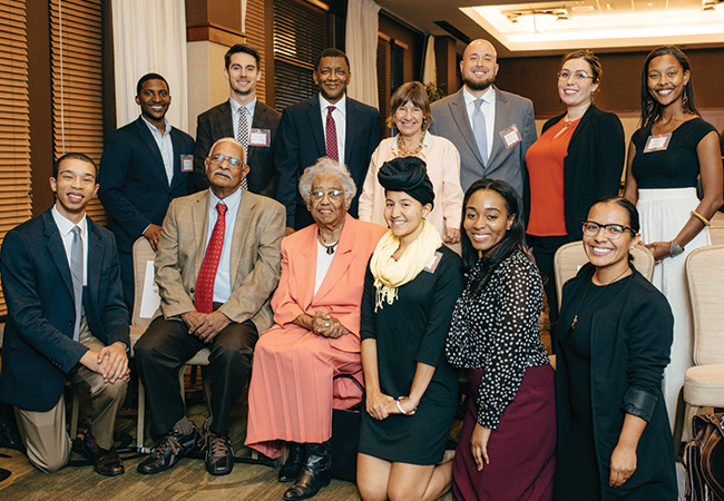 Dr. Constance E. Clayton sits in a peach colored skirt and blazer, surrounded by attendees at the 2016 Constance E. Clayton Lecture