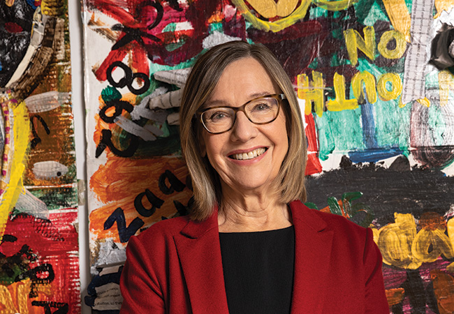 GSE Dean Pam Grossman smiles in front of a painted wall