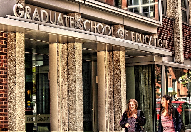 Two students walk in front of Penn GSE's building. 