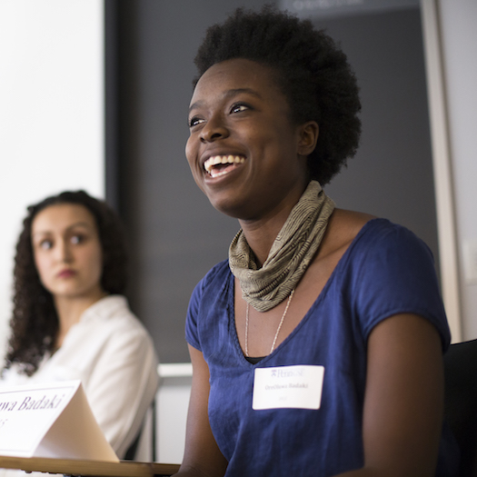 Two women sitting at table with name cards; one is smiling and speaking