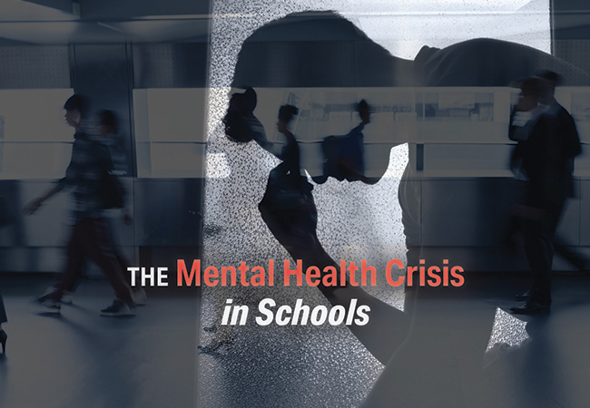 A black-and-white overlay featuring the silhouette of a slumped student holding his brow between his forefinger and thumb superimposed over blurred students and teachers bustling through a hallway with the words “The Mengal Health Crisis in Schools”