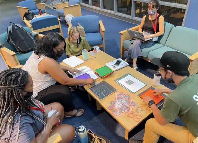 Teachers gathered around a table doing geometry puzzles with elastics