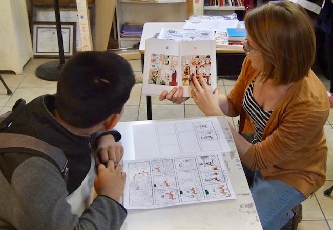 A tutor and a student read a graphic novel together. 