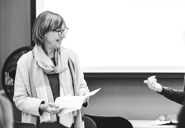 Pam Grossman holding a paper in front of a class