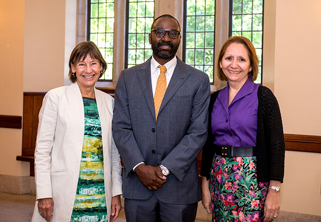 One woman in green dress, one man in suit, one woman in purple shirt.