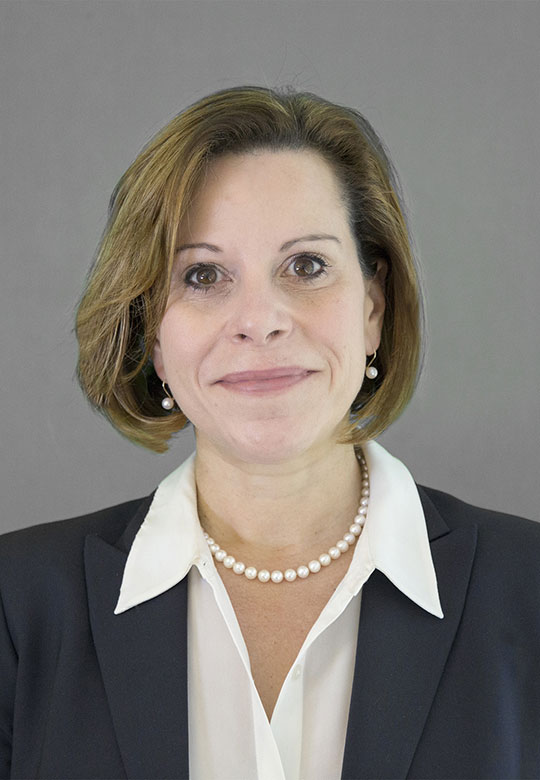 Woman with short hair and pearls.