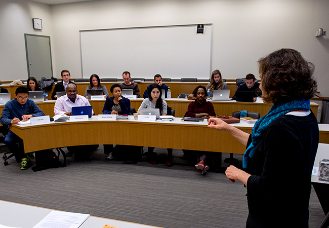 Female professor teaching classroom full of students.