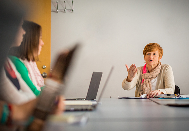 Female professor speaking to students on laptops.