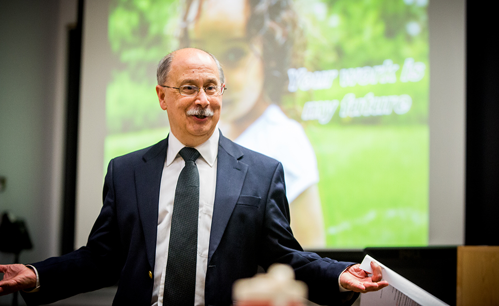 Male professor in glasses standing and talking.