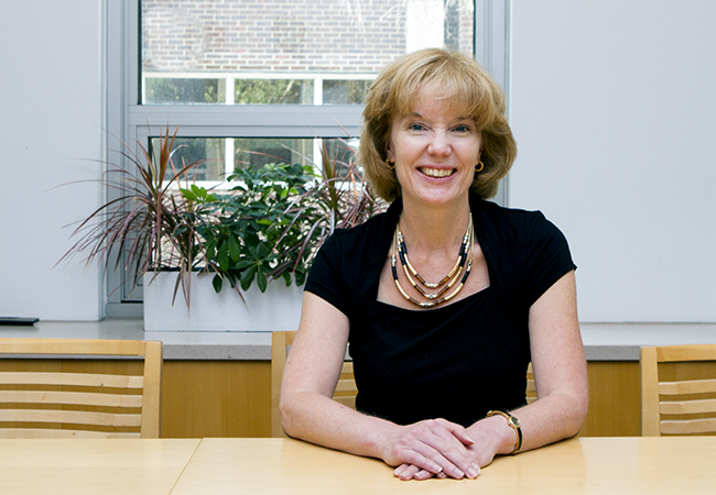 Smiling woman in black dress sitting at table.