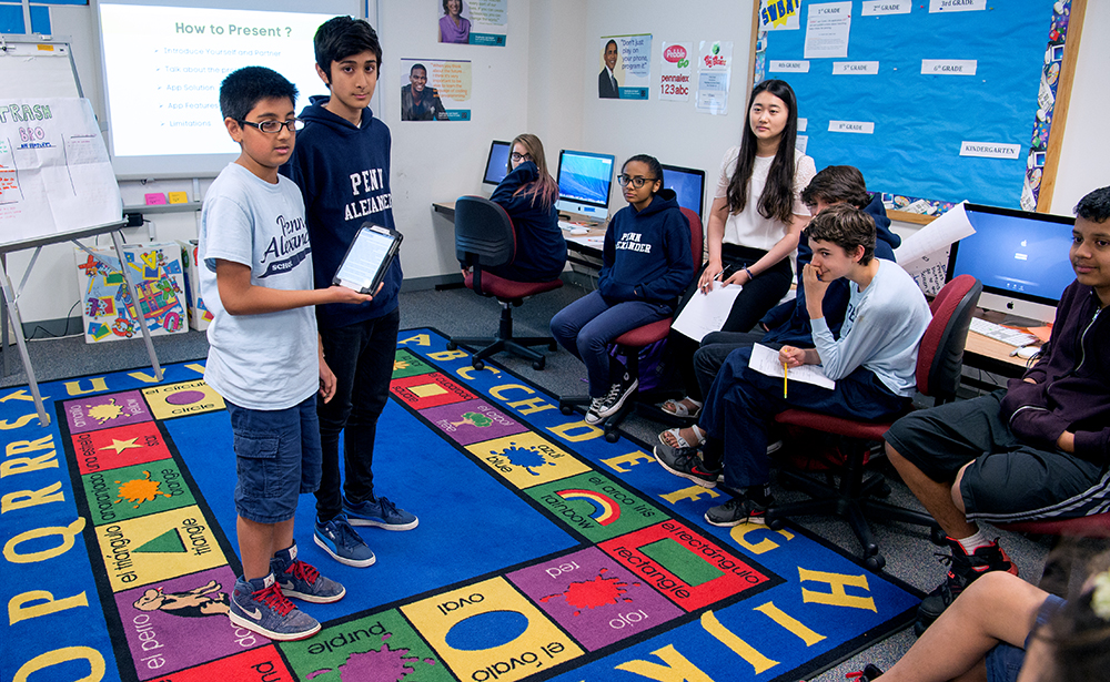 Middle school students with tablet standing at front of class