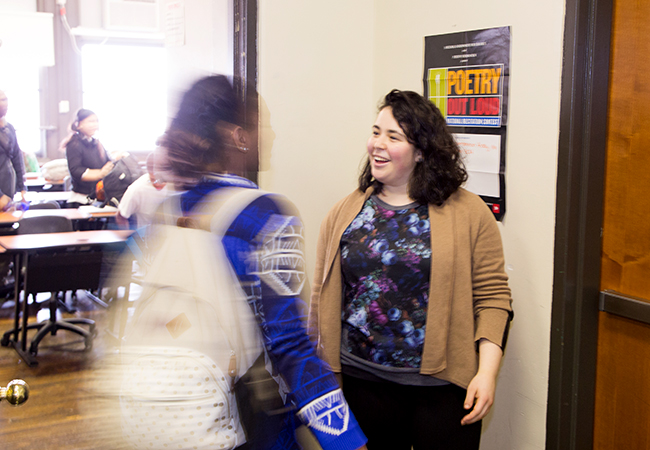 Female teacher greeting students at door.