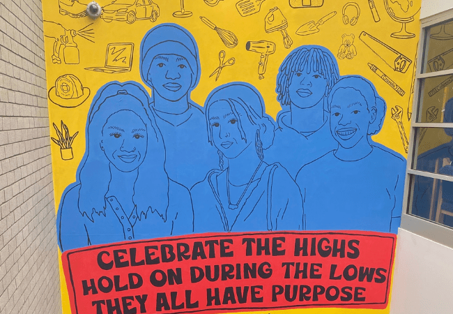 Photograph of mural depicting a group of students above the following quote: "Celebrate the highs. Hold on during the lows. They all have purpose."