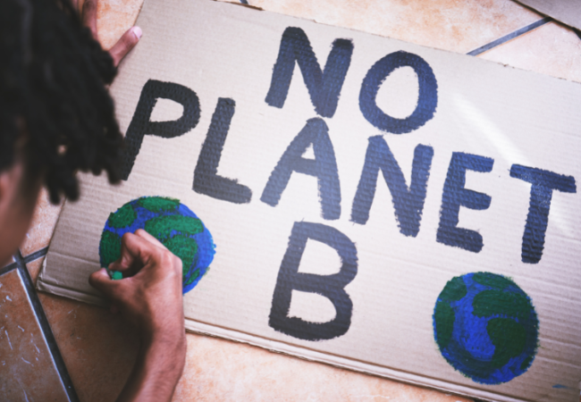 A student making a poster that says "No Planet B"