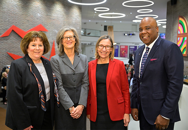 Susan Basso, Diane Eynon, Pam Grossman, and Lawrence P. Ward standing together at a gala event, dressed in suits and smiling.