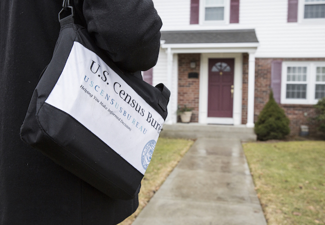 A U.S. Census worker approaches a house. 