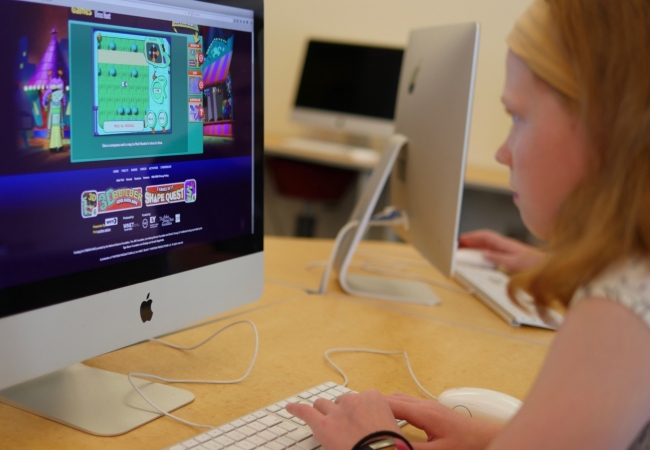 A child sits at a computer working on an online learning exercise. 