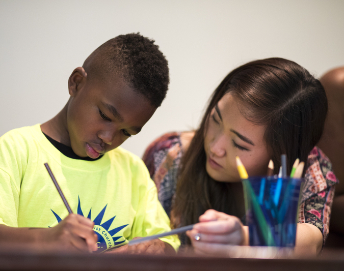 A student teacher draws with a young child in a summer enrichment program