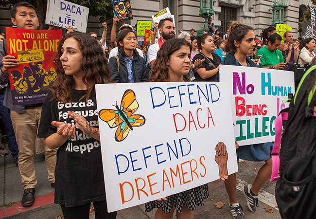 People hold signs in favor of DACA at a rally