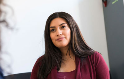 A woman wearing red listening to someone speak in an advising session