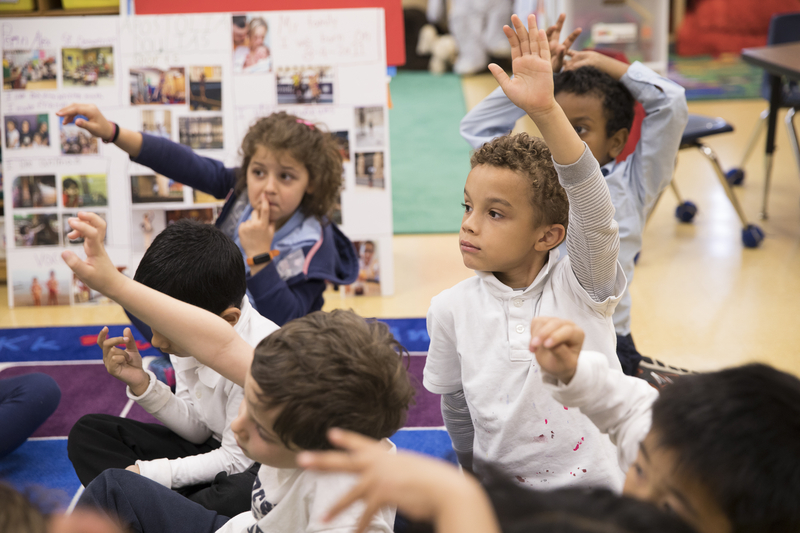 A boy raises his hand in a kindergarten class.