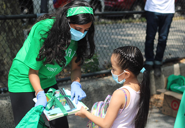 Rina Madhani showing a package of books to a small child.