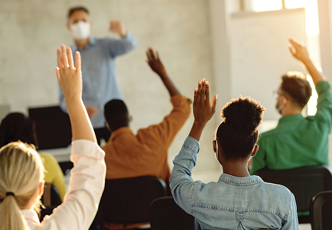 Students raising their hands in a classroom.