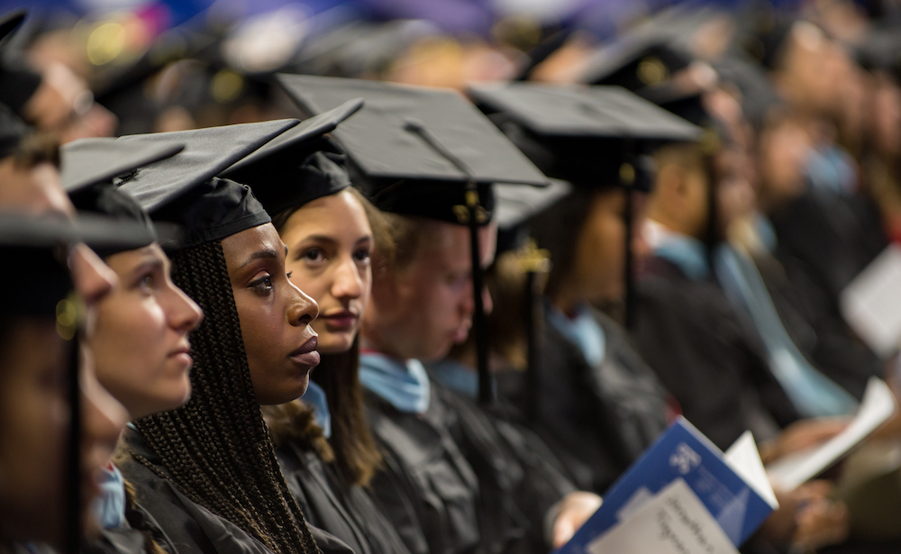 Graduates in caps and gowns sitting in the audience at Commencement