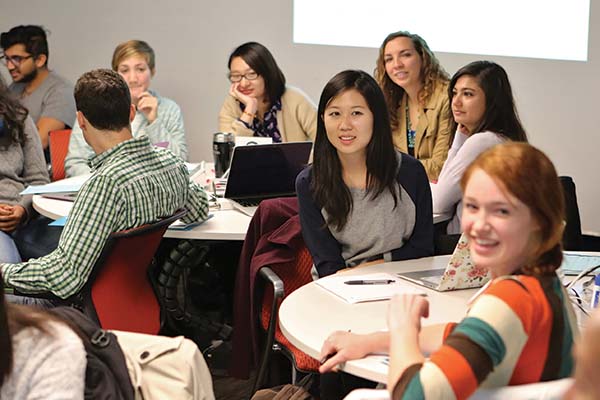 A heading reads “Scholarship and Fellowship” beside a photo of graduate students sitting at round tables, interacting with each other or looking ahead, with smiles on their faces.