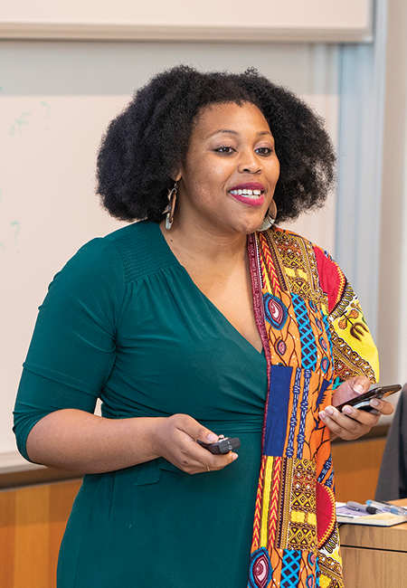 Woman in a colorful shawl is standing and speaking