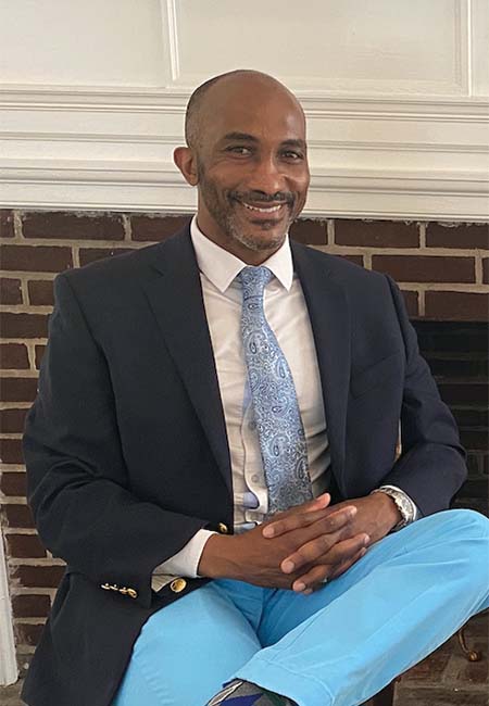 Delvin Dinkins seated with hands interlocked and wearing a suit. Photo courtesy of Karen Tracy