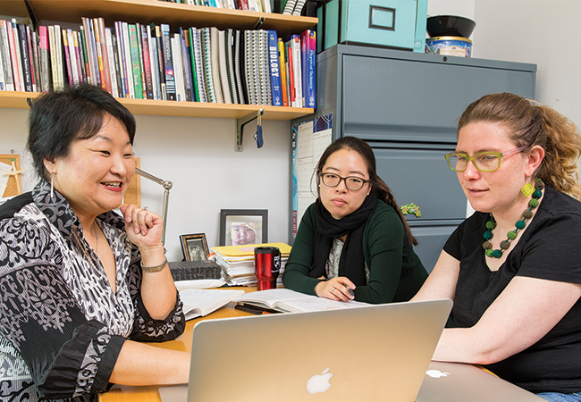 Three women sitting at a table and looking at a computer screen