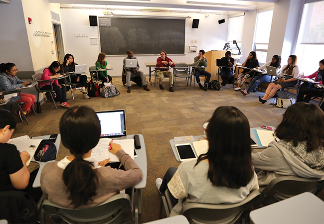 Penn GSE counseling students and faculty sit in a circle of desks in a classroom