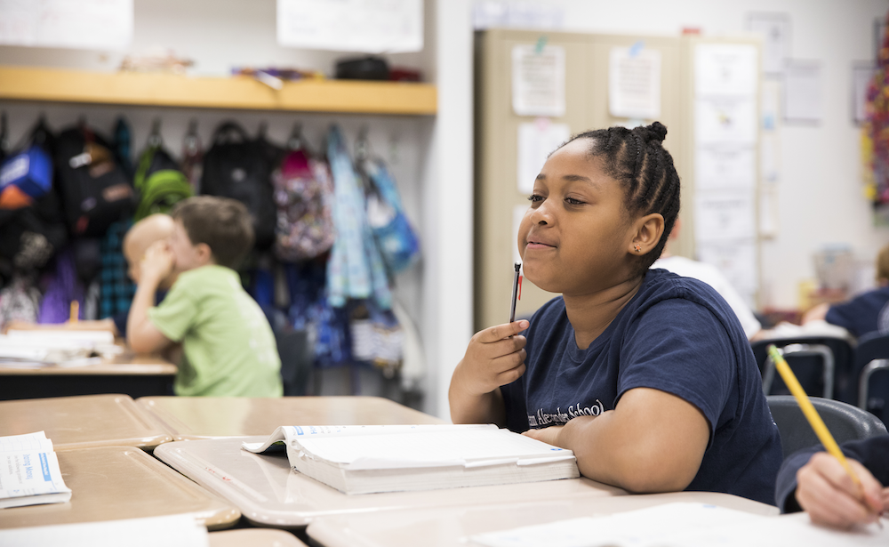 Philadelphia middle school student at a classroom desk tapping a pencil on her chin