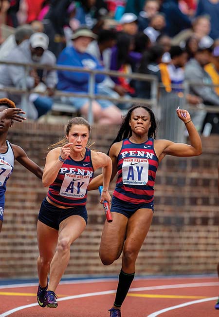 Female athletes race on the tracks in a stadium.