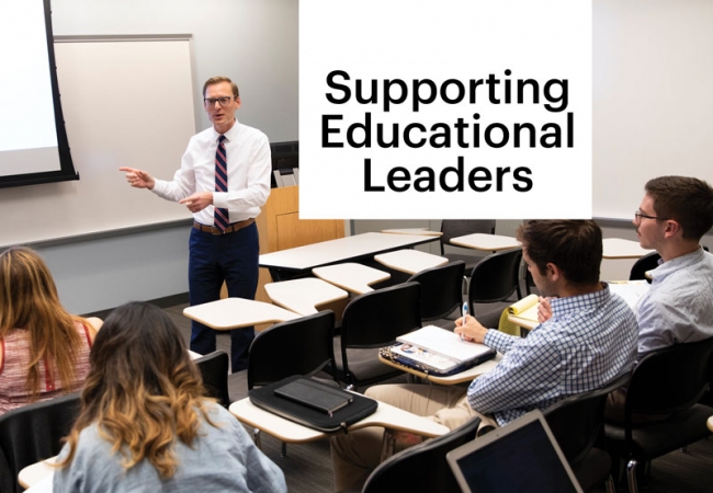 A professor wearing a white shirt and striped tie addresses a classroom of students who are listening and taking notes. The screen in the background has a large pi symbol] [Photo caption] Dr. Zachary Hermann is executive director of Penn GSE’s Center for Professional Learning, which offers virtual programs to support educators at various levels in the face of changing educational environments.