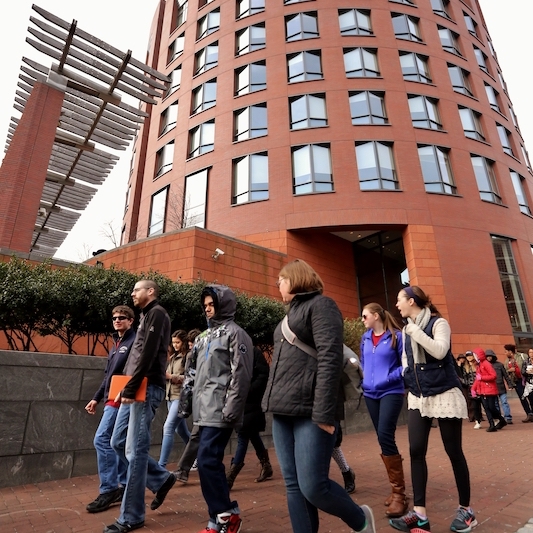 A group of students walks in front of Wharton's Huntsman Hall.