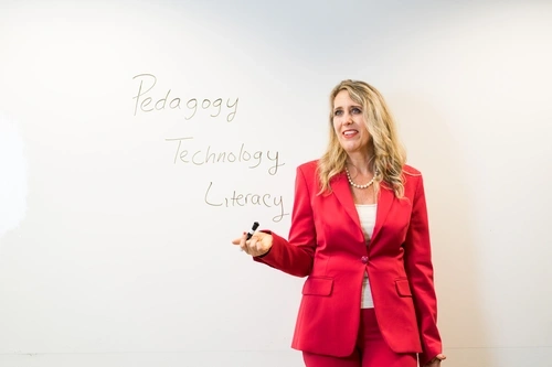 Dr. Amy Stornaiuolo standing in front a white board with the words "Pedagogy, Technology, Literacy" written.