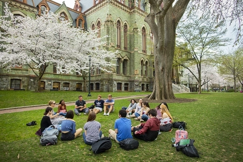 Class of students sitting outside on the grass in front of College Hall