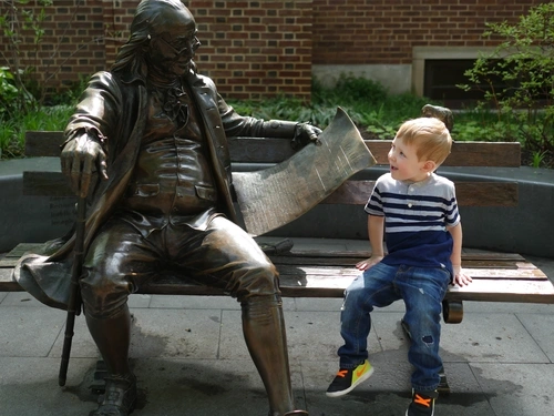 Three year boy looking up at the Ben Franklin statue on campus