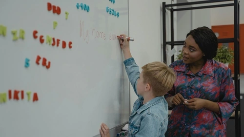 Adolescent child and teacher writing on the whiteboard