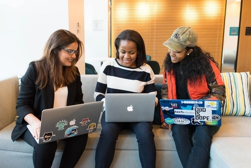 Three females sitting with laptops smiling