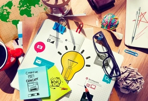 Bright and colorful picture of a light bulb and post-its on a design board